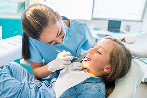 Girl in dental chair getting an exam from dentist