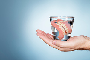  Patient's hand holding dentures that were provided by Mountain State Oral and Facial Surgery in Hurricane, WV
