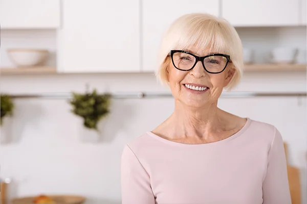 Joyful nice woman standing in the kitchen with an implant supported bridge from Mountain State Oral and Facial Surgery in Charleston, WV