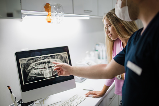 Dentist reviewing a digital x-ray with assistant at Mountain State Oral and Facial Surgery in Hurricane, WV