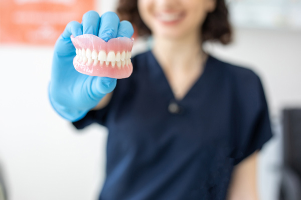 Woman holding a set of dentures from Mountain State Oral and Facial Surgery in Charleston, WV