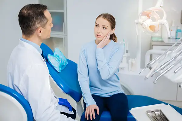 Concerned patient discussing her tooth pain with her dentist before tooth extraction while sitting in a dental chair at Mountain State Oral and Facial Surgery in Charleston, WV