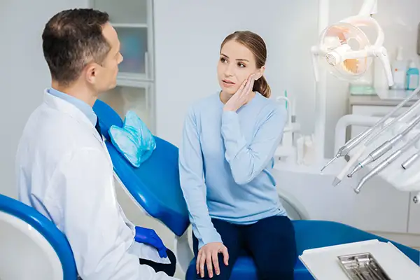 Concerned patient discussing her tooth pain with her dentist before tooth extraction while sitting in a dental chair at Mountain State Oral and Facial Surgery in Hurricane, WV Concerned patient discussing her tooth pain with her dentist before tooth extraction while sitting in a dental chair at Mountain State Oral and Facial Surgery in Hurricane, WV