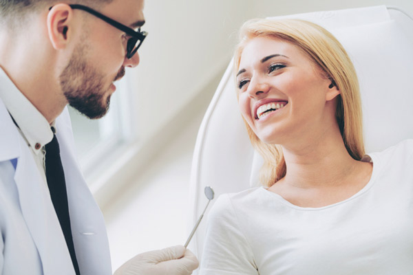 Woman smiling while oral surgeon talks about oral surgery at Mountain State Oral and Facial Surgery in Hurricane, WV