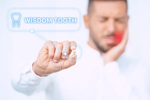 A man holding an extracted wisdom tooth while touching his jaw in pain, with a digital label indicating 'Wisdom Tooth.'